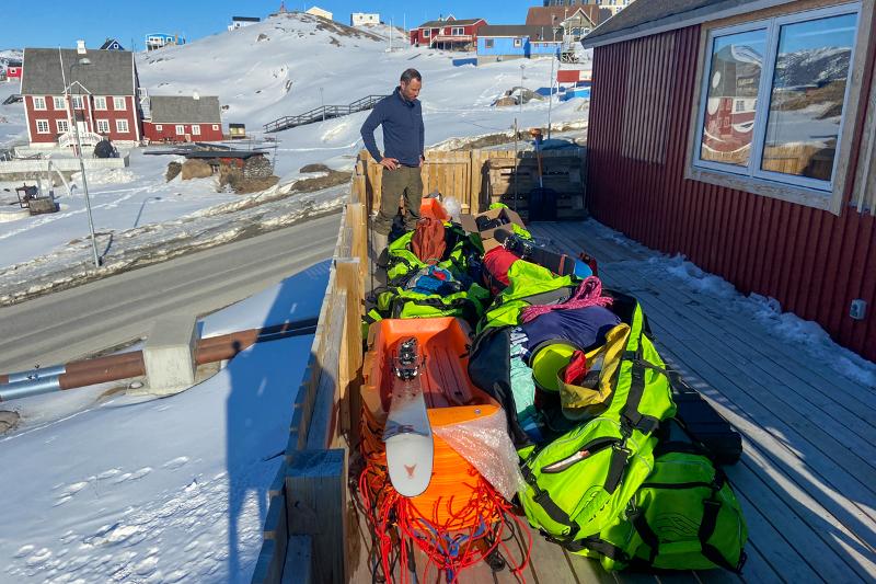 Ein mann på ein veranda på illusta, grønland. Ser poå m,asse utstyr ski og liknande.
